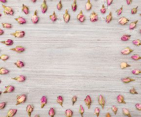frame from rose flower buds on wooden plank