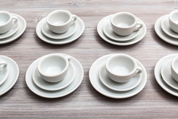 several white cups and saucers on gray brown board
