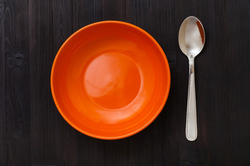 orange bowl and spoon on dark brown table