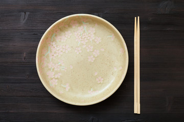 top view yellow plate and chopsticks on brown