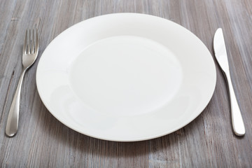 white plate, knife, spoon on gray brown table