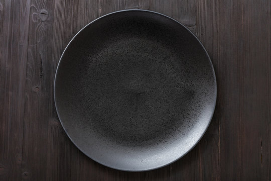 Top View Of Black Plate On Dark Brown Table