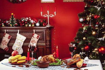 Christmas dinner by candlelight, table setting. Thanksgiving table with baked turkey in a decorated room with a Christmas tree.