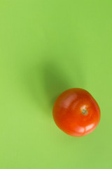 One red tomato on a green background