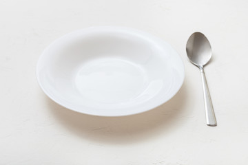 white deep plate and spoon on plaster