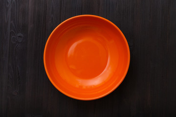 top view of orange bowl on dark brown table