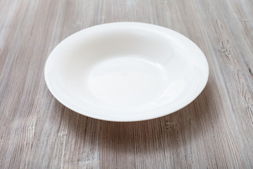 white deep plate on gray brown board