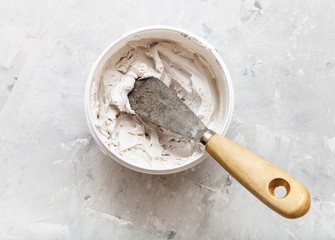 metal spatula with wooden handle in pot with putty