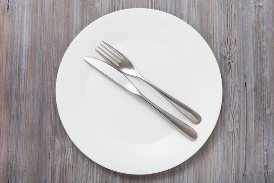 top view of white plate with flatware on gray