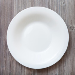 top view of white deep plate on gray brown table