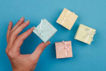 hand holding a small gift box on blue background