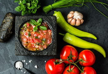 Tomato sauce salsa and ingredients dark stone background. Top view