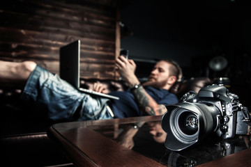 Male head lying on the sofa in his office, working on laptop and talking on a cell phone. The...