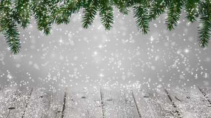 christmas background - snowfall  with a border of christmas fir branches over wooden planks