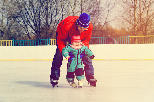 father and little daughter learning to skate in winter