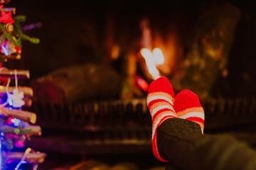 Fototapeta na wymiar Woman feet in wool socks warming by fireplace