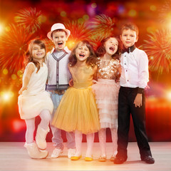 Group of happy kids in holiday clothes with fireworks background