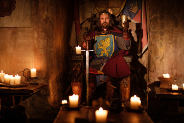 Fototapeta na wymiar Medieval king on throne in ancient castle interior.