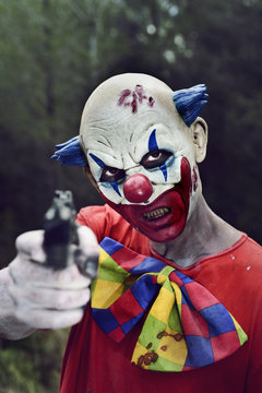 scary evil clown with a gun