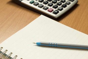 Pen placed on the book with calculator background