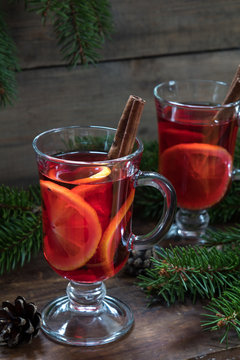 Two glasses cup of delicious Christmas hot mulled wine with oranges and spices on wooden background