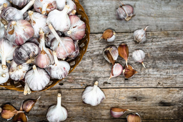 Fresh garlic in the basket, top view. Farm vegetables on wooden table.