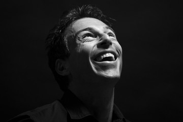 Isolated man face laughing . Black background, black and white picture