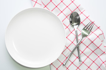 knife white plate and fork spoon on red checked tablecloth