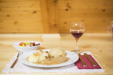 Mashed potato with pork meat, salad and glass of red wine on tab