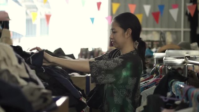 Happy Asian mixed race girl looking for good cheap clothes in sale bazaar