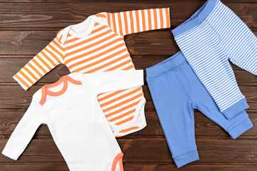 Two babies bodysuits and pants on wooden background. Baby clothe