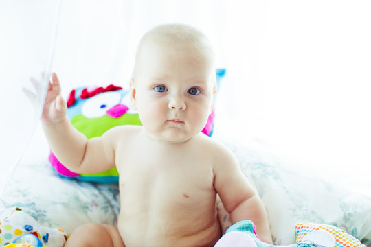 Baby-boy with blue eyes raises his little hand up