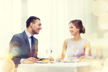 Obraz na płótnie Canvas smiling couple eating main course at restaurant