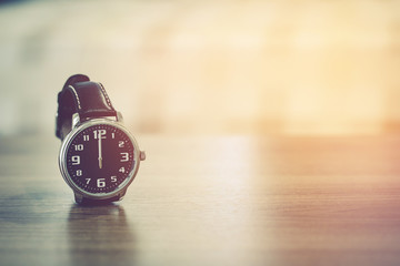 wristwatch on the table with blur bedroom background, the time show midday or midnight