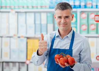 Supermarket clerk holding tomatoes