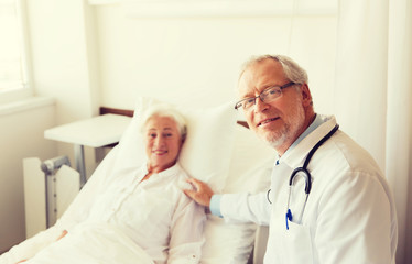 doctor visiting senior woman at hospital ward