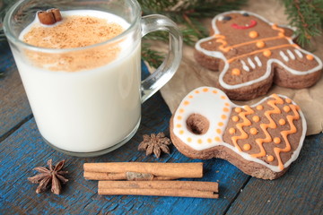 milk with cinnamon in a transparent mug, waffles, cakes, tied with Christmas ribbon, anise on blue wooden background