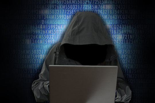 Unrecognizable hacker in front of computer – cybercrime concept