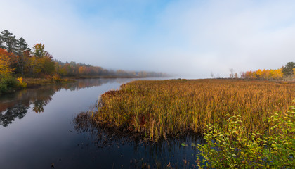 Morning mist and fog rises from warm water into autumn October air on Corry lake, Ontario, Canada.