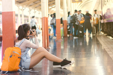 Orange helmet and backpack at the train station with tourists. Travel ideas