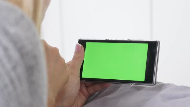 Female blond relaxing at home with green screen display smart phone 4K 2160p 30fps UltraHD footage - Blond hair woman in the bed with chroma key tablet 3840X2160 UHD video