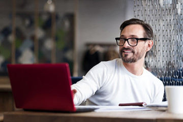 Bearded man with glasses working on laptop
