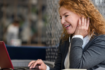 Side view of smiling woman using laptop