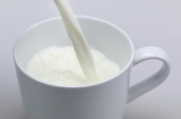 pouring a glass of milk creating splash on a white background