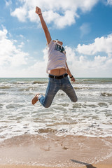 Obraz premium Young man jumping on the beach in the oncoming waves