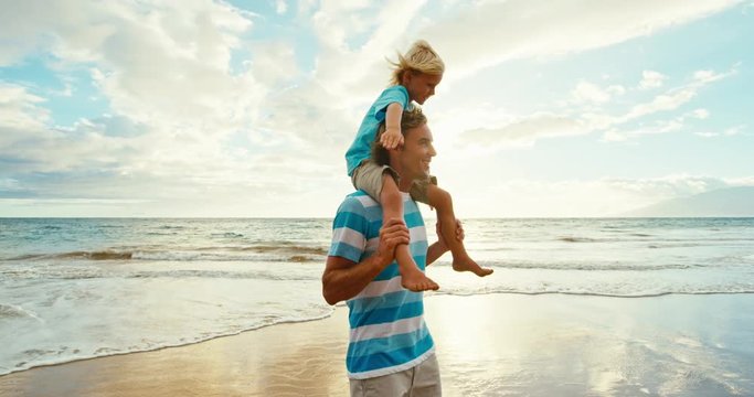 Father and son walking and playing having fun on the beach at sunset