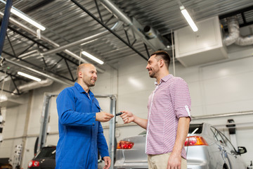 auto mechanic giving key to man at car shop