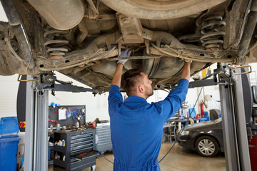 mechanic man or smith repairing car at workshop