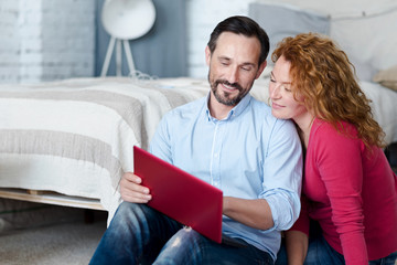 Couple sitting on floor and using laptop