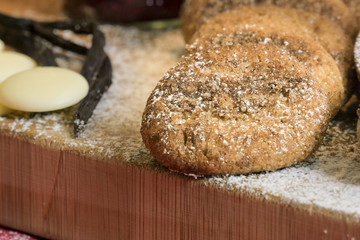 cookies and biscuits presented on a wooden board with ingredients next to it